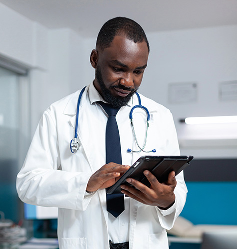 African american therapist doctor analyzing medicine prescription using tablet computer checking sickness expertise during medical appointment. Practitioner man working in hospital office